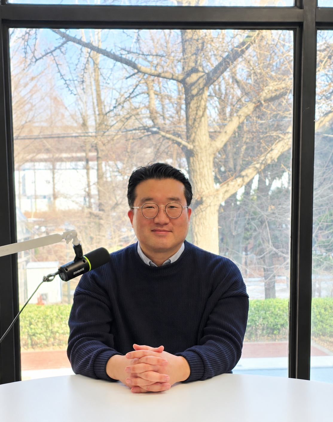 마이크 앞에서 두 손을 모으고 앉아 있는 정진 소장